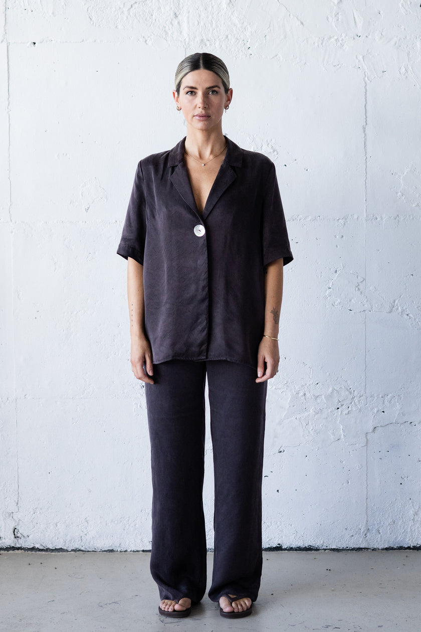 Woman wearing a dark outfit against a white wall